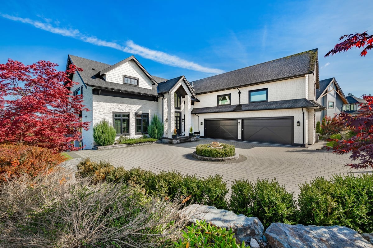 Elegant estate with manicured lawn, cobblestone driveway, and fountain